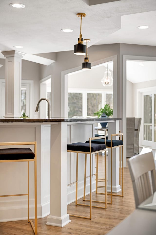 kitchen with recessed lighting, white cabinetry, decorative columns, and light wood-style flooring