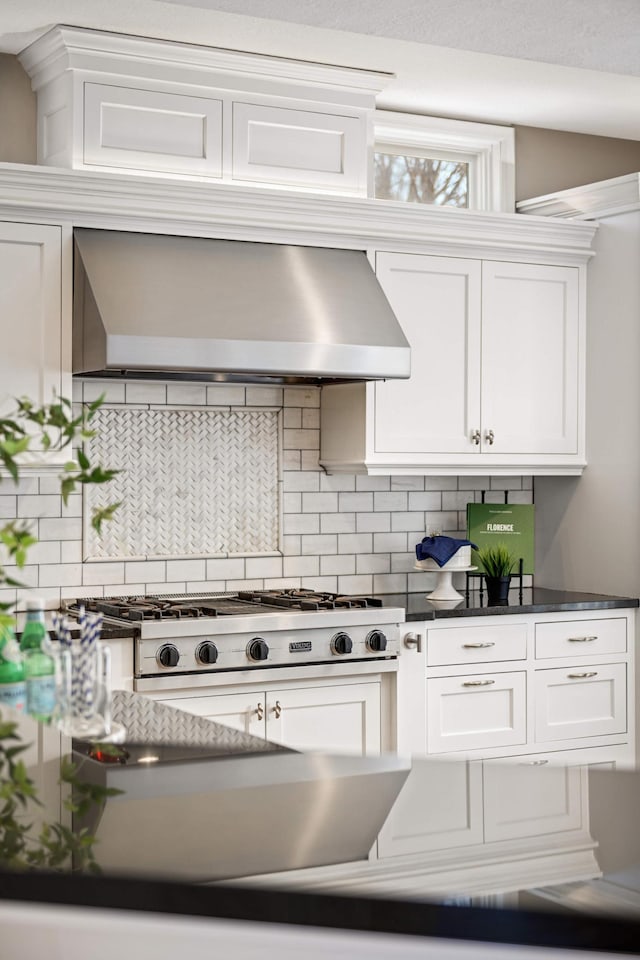 kitchen with decorative backsplash, dark countertops, white cabinetry, and wall chimney exhaust hood