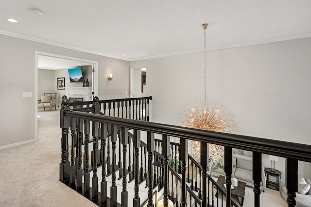 corridor with carpet floors, a notable chandelier, crown molding, and an upstairs landing