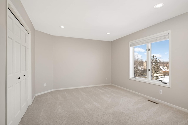 unfurnished bedroom featuring light carpet, a closet, visible vents, and baseboards