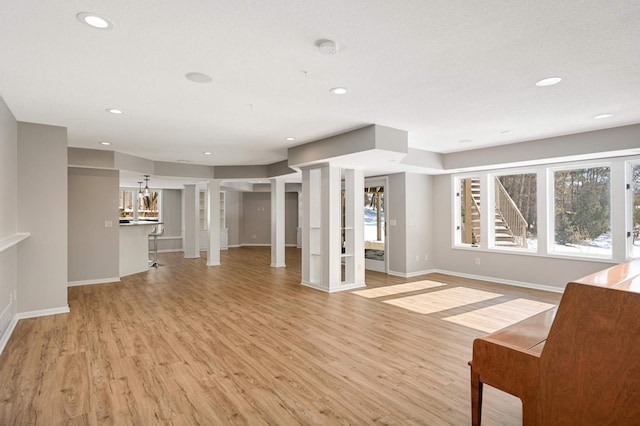 unfurnished living room featuring recessed lighting, ornate columns, baseboards, and light wood finished floors