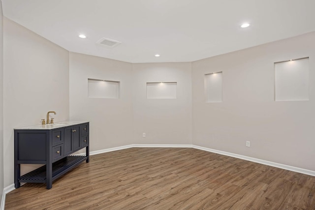 empty room with recessed lighting, a sink, baseboards, and wood finished floors