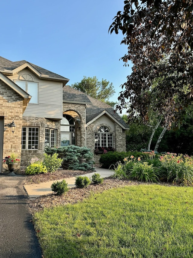 view of front of house featuring brick siding and a front yard