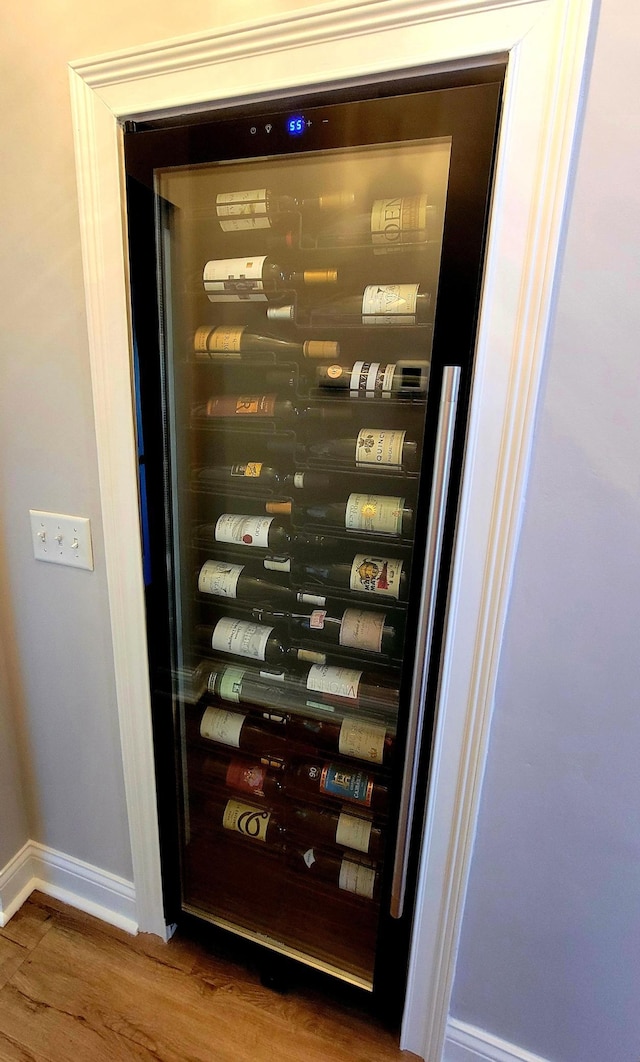 wine room featuring beverage cooler, wood finished floors, and baseboards