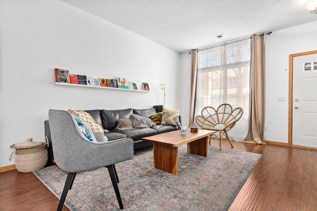 living area with a textured ceiling, baseboards, and wood finished floors