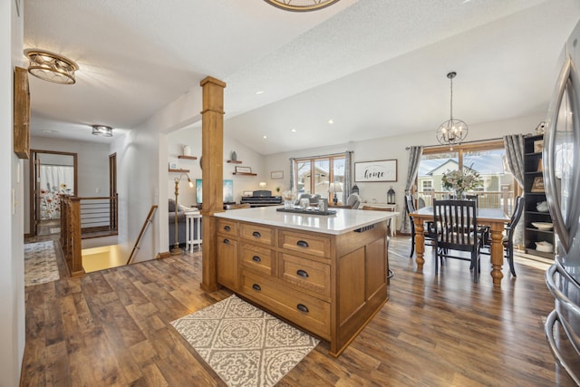 kitchen featuring lofted ceiling, freestanding refrigerator, hanging light fixtures, a center island, and light countertops