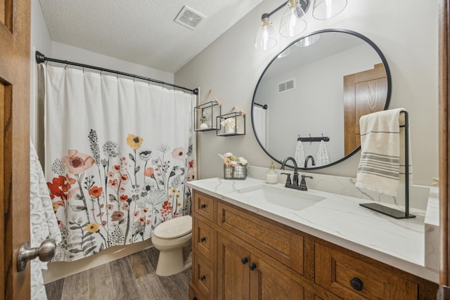 bathroom featuring visible vents, a textured ceiling, toilet, and wood finished floors