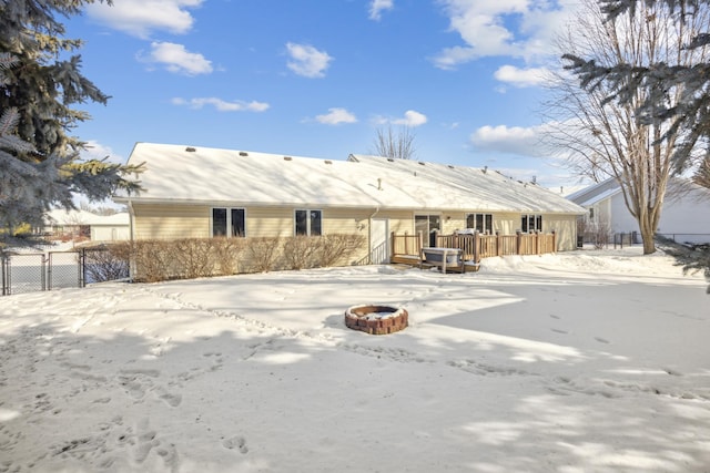 snow covered back of property with fence and a fire pit