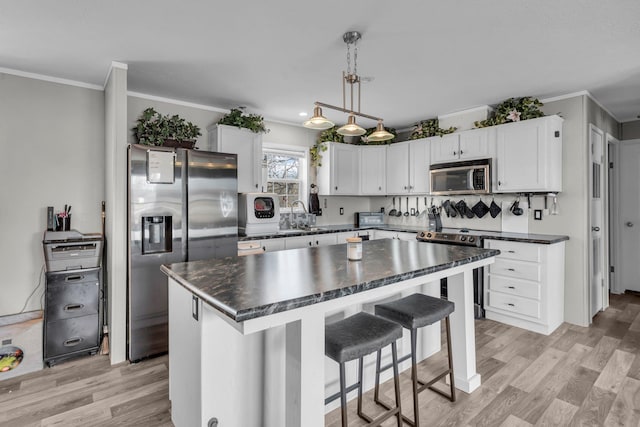27939 Forest Blvd, Wyoming, MN 55092 - kitchen with stainless steel appliances, dark countertops, ornamental molding, white cabinets, and light wood-style floors