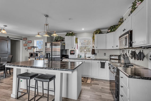 27939 Forest Blvd, Wyoming, MN 55092 - kitchen featuring appliances with stainless steel finishes, dark countertops, light wood finished floors, white cabinets, and a kitchen island