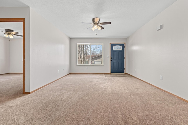 foyer featuring baseboards, light colored carpet, and a textured ceiling