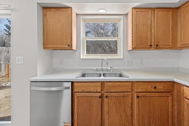 kitchen with tasteful backsplash, a sink, light countertops, and stainless steel dishwasher