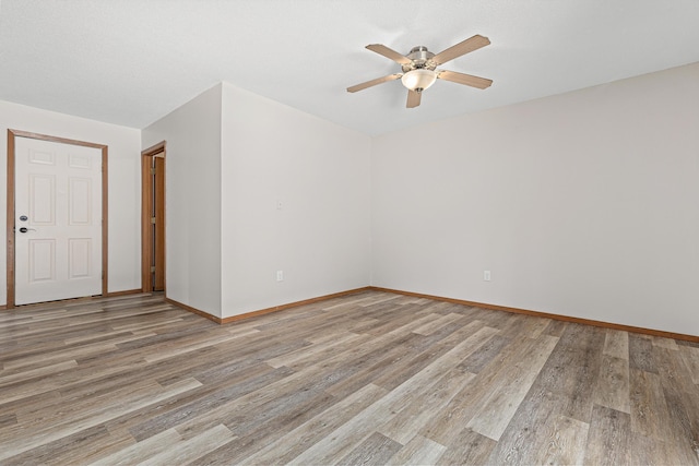 empty room with baseboards, light wood-style floors, and a ceiling fan