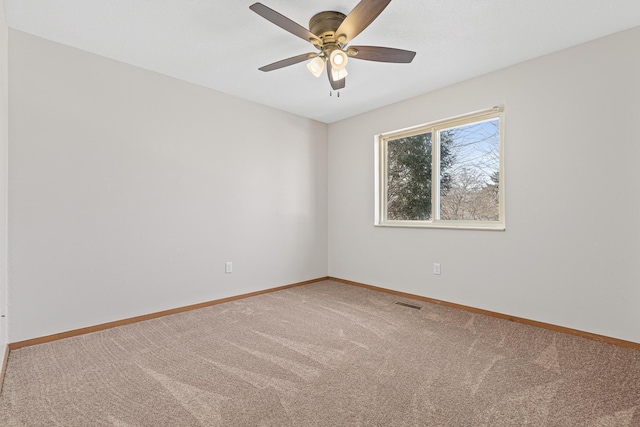 carpeted spare room with visible vents, a ceiling fan, and baseboards