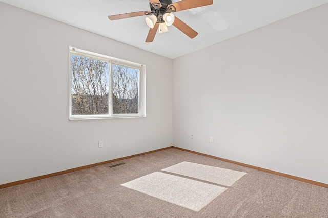 carpeted spare room with visible vents, a ceiling fan, and baseboards