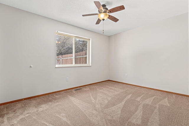 carpeted empty room featuring visible vents, ceiling fan, a textured ceiling, and baseboards