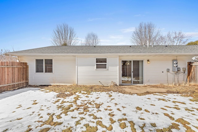 back of property featuring a shingled roof and fence