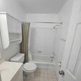 bathroom with shower / tub combo, tile patterned flooring, vanity, and toilet