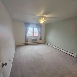 empty room with a baseboard radiator and a ceiling fan