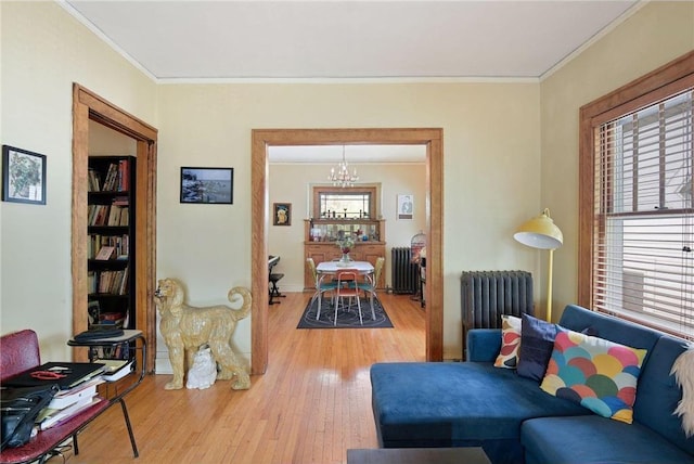 living room featuring ornamental molding, a notable chandelier, radiator heating unit, and wood finished floors