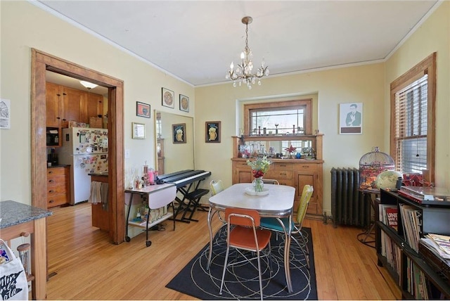 dining area featuring radiator, a notable chandelier, light wood-type flooring, and crown molding