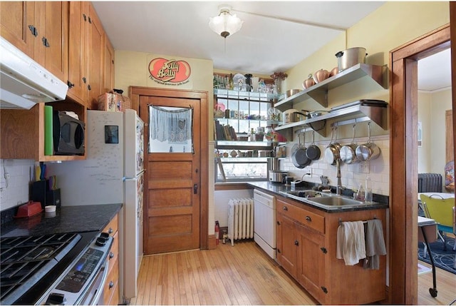 kitchen featuring stainless steel range with gas cooktop, radiator, dishwasher, brown cabinetry, and dark countertops