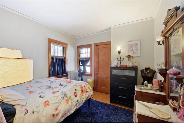 bedroom with crown molding, light wood finished floors, and radiator heating unit