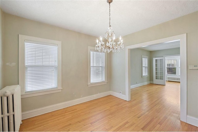 unfurnished room with light wood finished floors, radiator heating unit, and baseboards