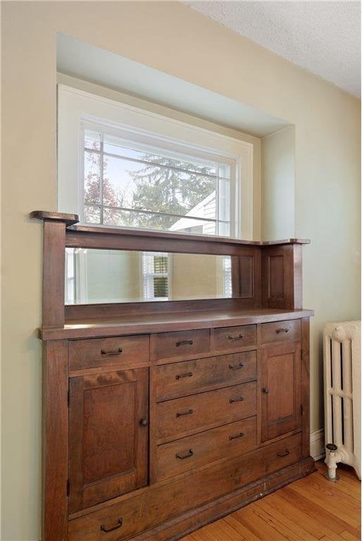 interior details featuring a textured ceiling, radiator heating unit, and wood finished floors