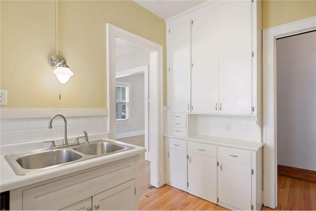 kitchen featuring white cabinets, light countertops, a sink, and decorative backsplash