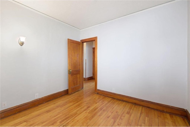 unfurnished room featuring light wood-style flooring, baseboards, and ornamental molding