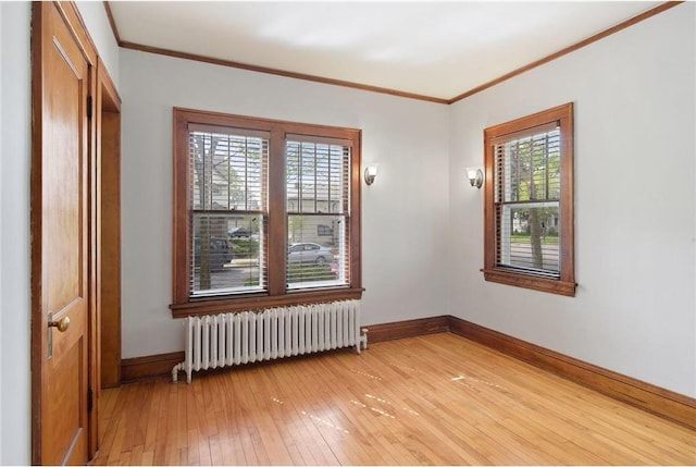 unfurnished room with baseboards, ornamental molding, light wood-style flooring, and radiator