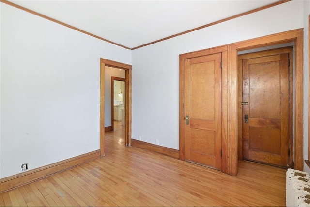 unfurnished bedroom with ornamental molding, light wood-type flooring, radiator heating unit, and baseboards