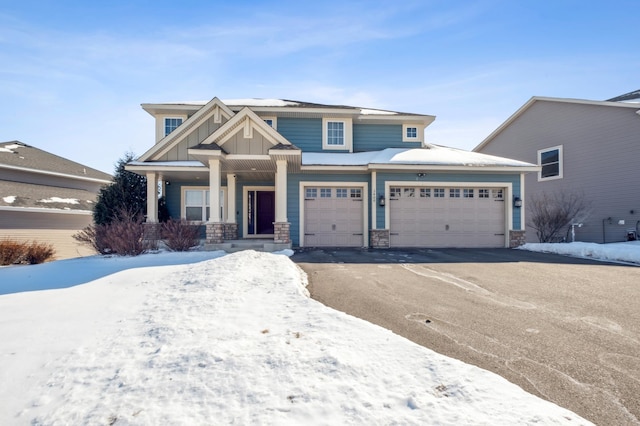 view of front of property featuring covered porch, stone siding, aphalt driveway, and board and batten siding