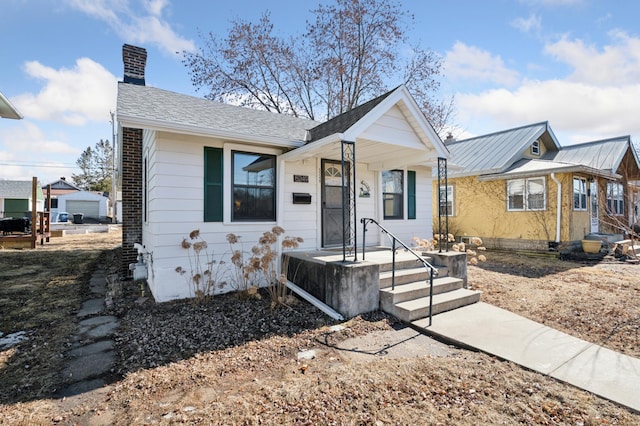 bungalow-style house featuring metal roof and a chimney