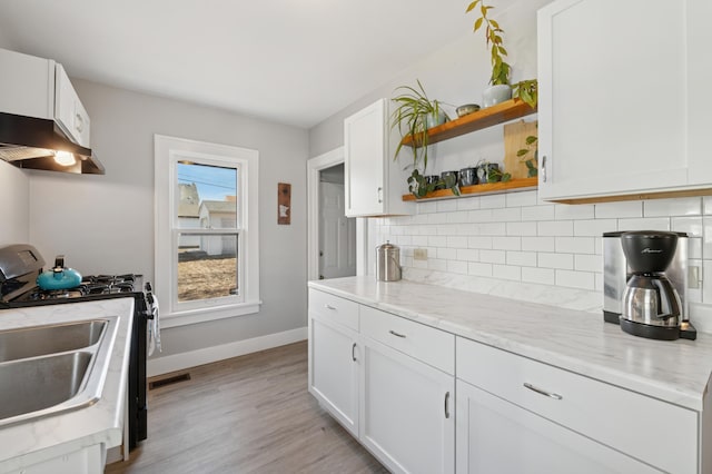 kitchen featuring open shelves, under cabinet range hood, backsplash, white cabinets, and gas range