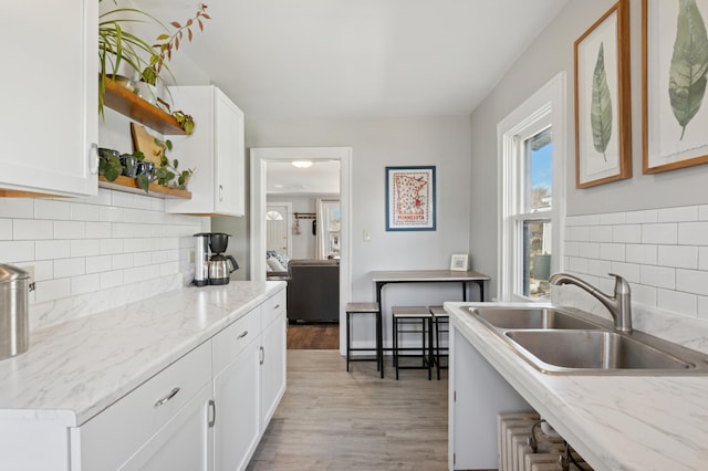 kitchen featuring open shelves, white cabinetry, light wood-style flooring, and a sink