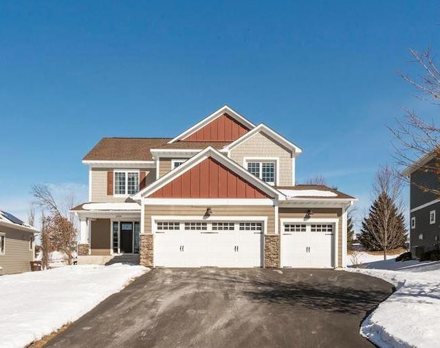 craftsman inspired home featuring stone siding, aphalt driveway, and board and batten siding