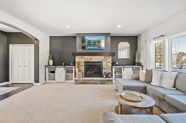 living area featuring carpet floors, arched walkways, a fireplace, recessed lighting, and baseboards