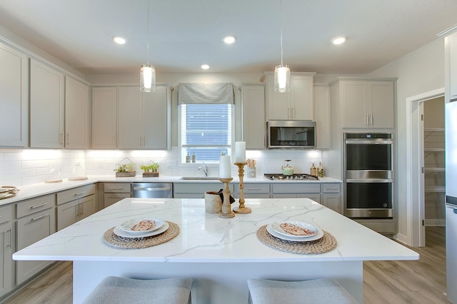 kitchen with a kitchen bar, gray cabinets, stainless steel appliances, and decorative light fixtures