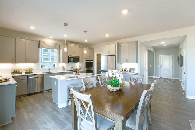 4601 Percheron Blvd, Chaska, MN 55318 - kitchen with tasteful backsplash, light countertops, appliances with stainless steel finishes, a kitchen island with sink, and light wood-style floors