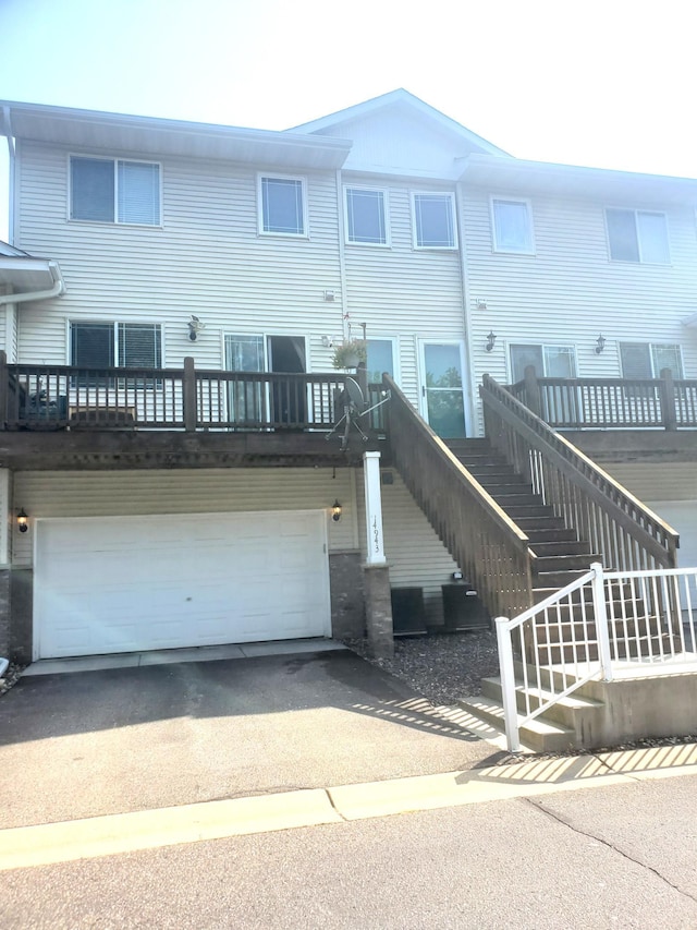 multi unit property with driveway, an attached garage, and stairs