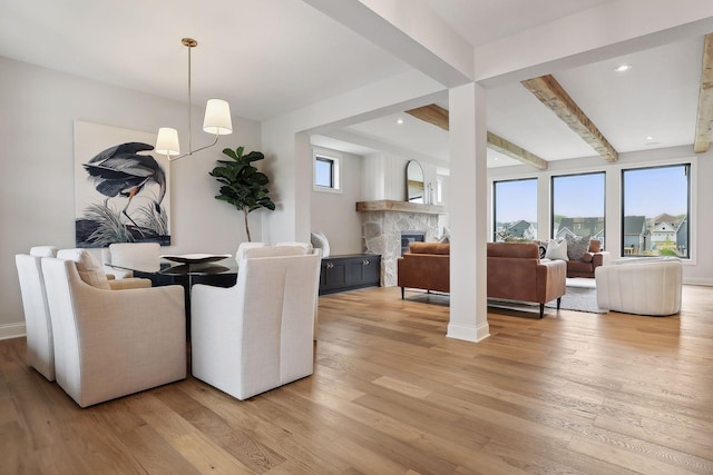 dining area with light wood-type flooring, a fireplace, beam ceiling, and recessed lighting