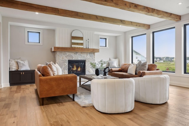 living area featuring a stone fireplace, light wood-style flooring, recessed lighting, baseboards, and beamed ceiling