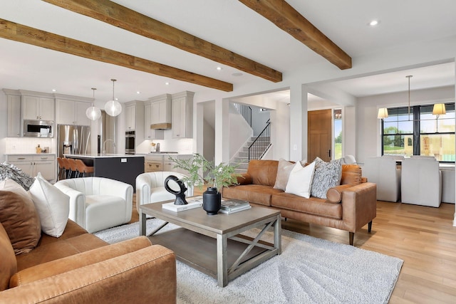 living area featuring recessed lighting, beam ceiling, stairway, and light wood finished floors