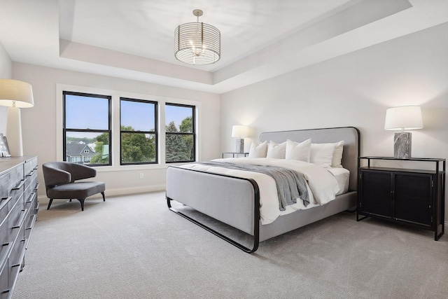 bedroom with baseboards, a tray ceiling, a notable chandelier, and light colored carpet