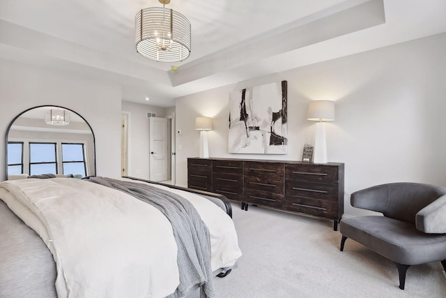 bedroom featuring light carpet, a raised ceiling, and a chandelier