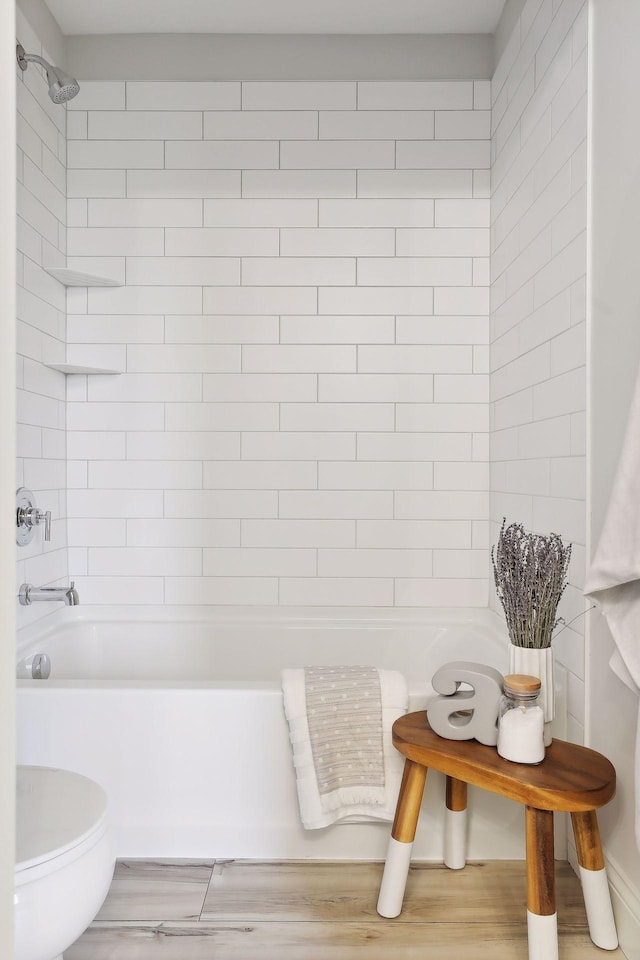 bathroom featuring bathing tub / shower combination, toilet, and wood finished floors