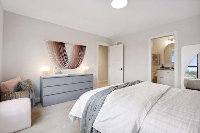 carpeted bedroom with ensuite bath, visible vents, and baseboards