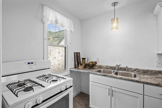 kitchen with dark countertops, hanging light fixtures, white cabinetry, white range with gas cooktop, and a sink